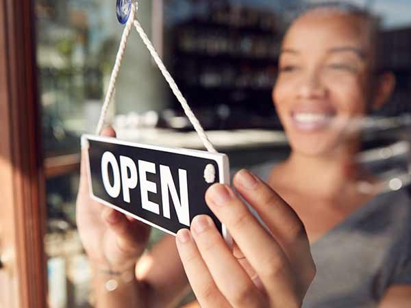 Women at small business with open sign